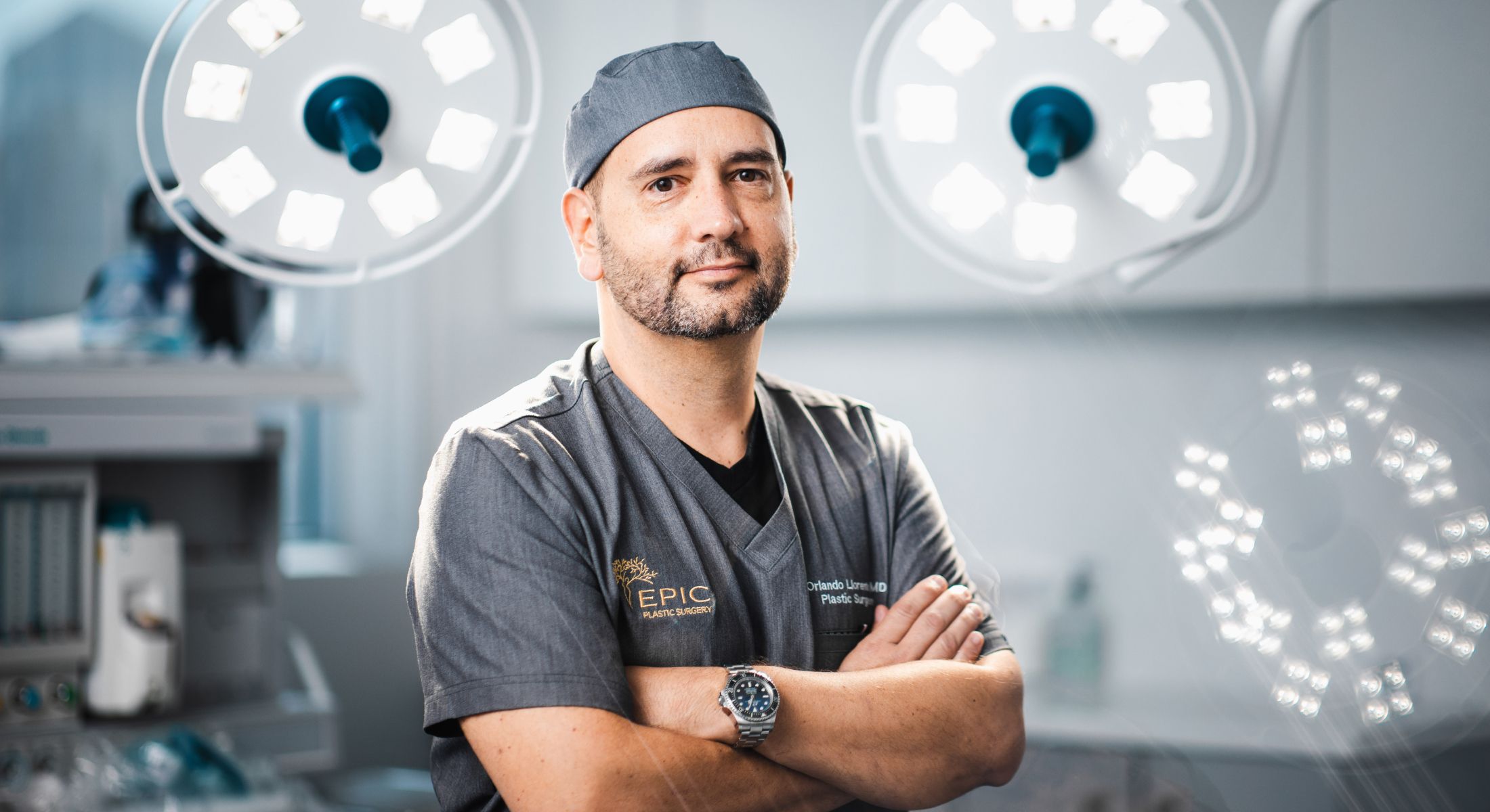 Surgeon in scrubs with operating lights background.