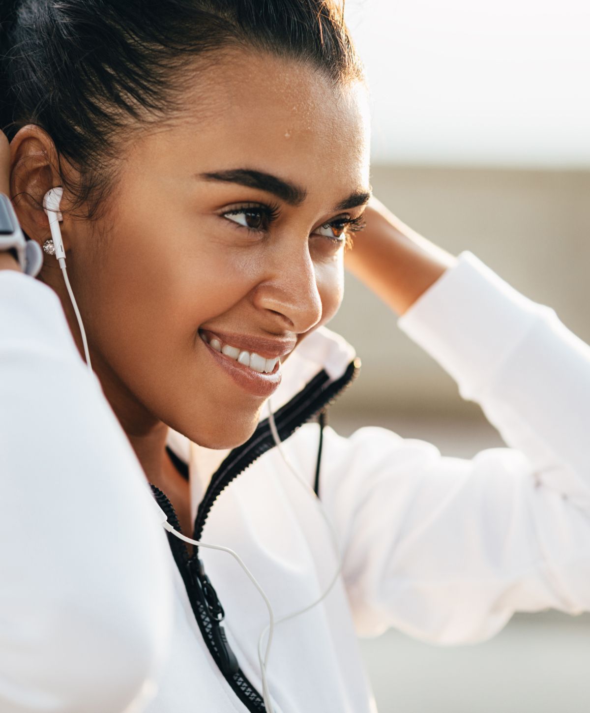 Smiling woman adjusting earbuds in workout attire.