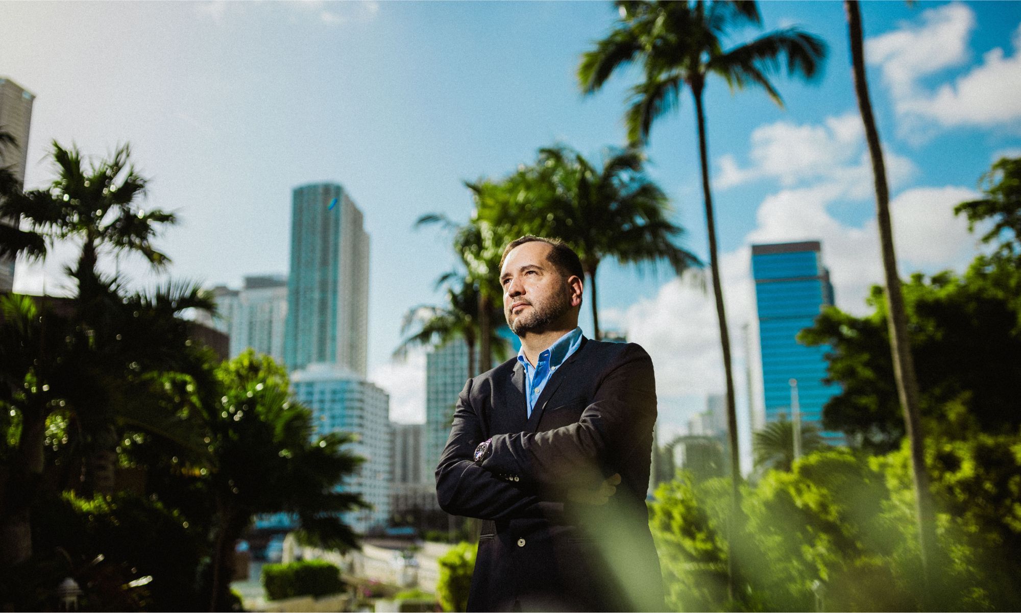 Man in suit with city skyline and palm trees.