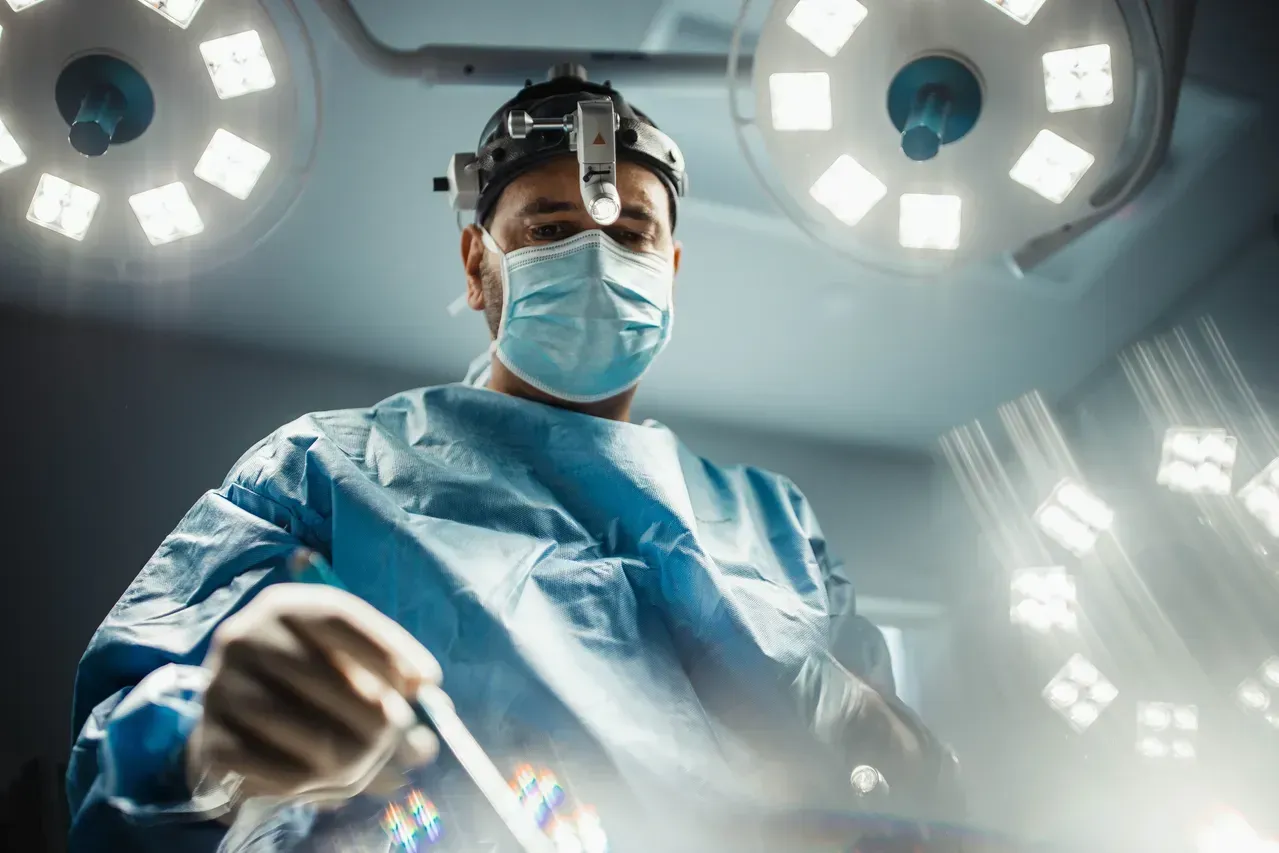 Surgeon preparing for a medical procedure under lights.