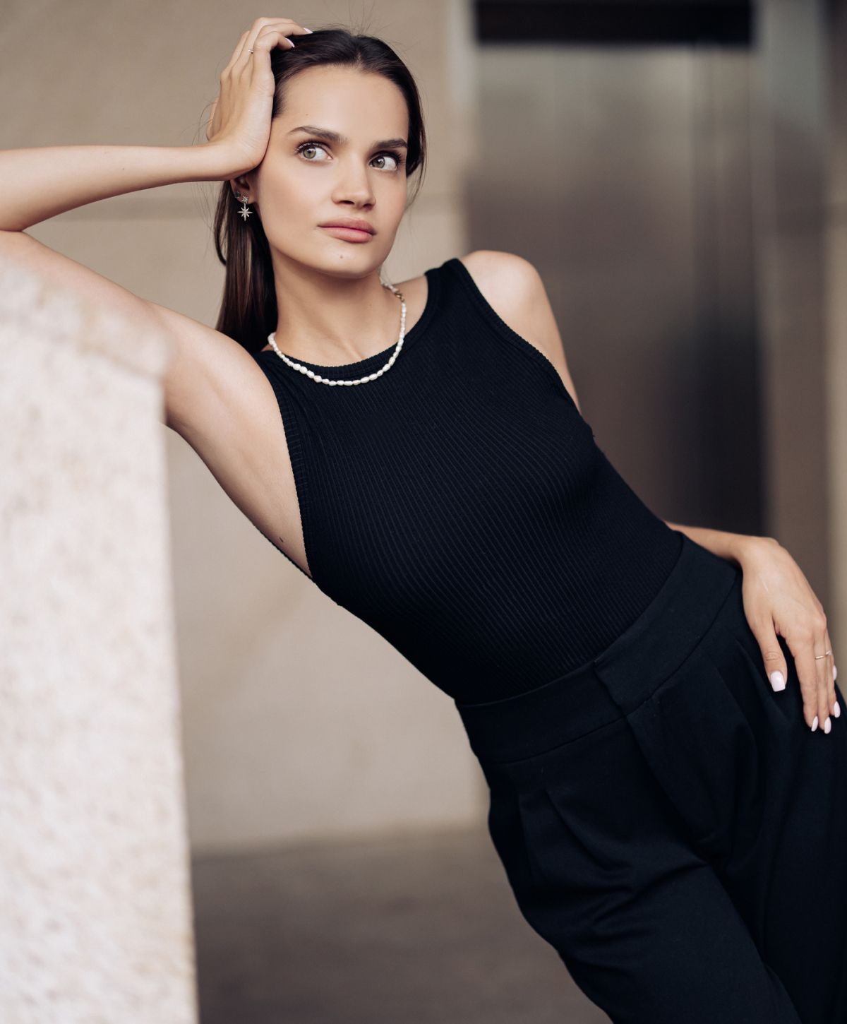 Model in stylish black outfit, posed elegantly.