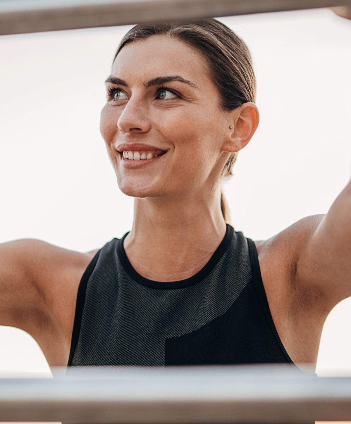 Smiling woman exercising outdoors in athletic wear.