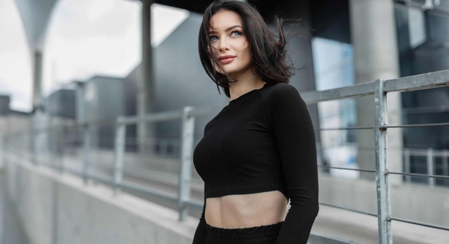 Woman in black outfit posing outdoors.