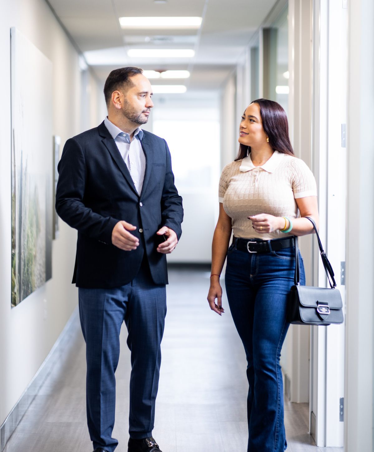 Two professionals engaged in conversation in corridor.